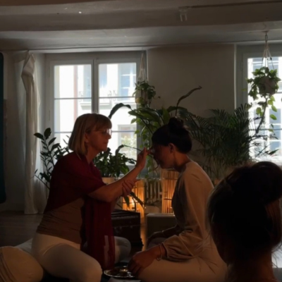 Erika Stalder | ganzheitlicher yoga (3) Frau in Yogakleider klemmt eine aufgerollte Yogamatte unter den Armen