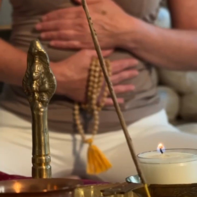 Erika Stalder | ganzheitlicher yoga (3) Sitzende Frau hält in der rechten Hand eine Mala Kette.